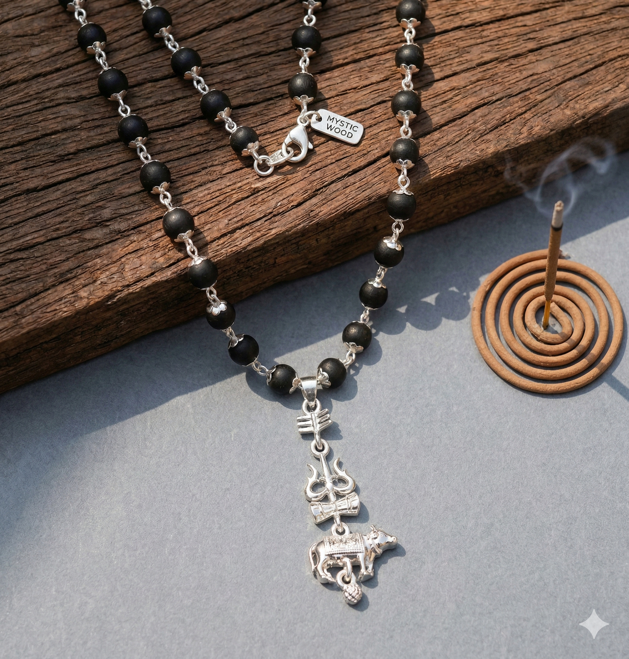 Black beaded necklace with silver charms on a wooden surface with incense.