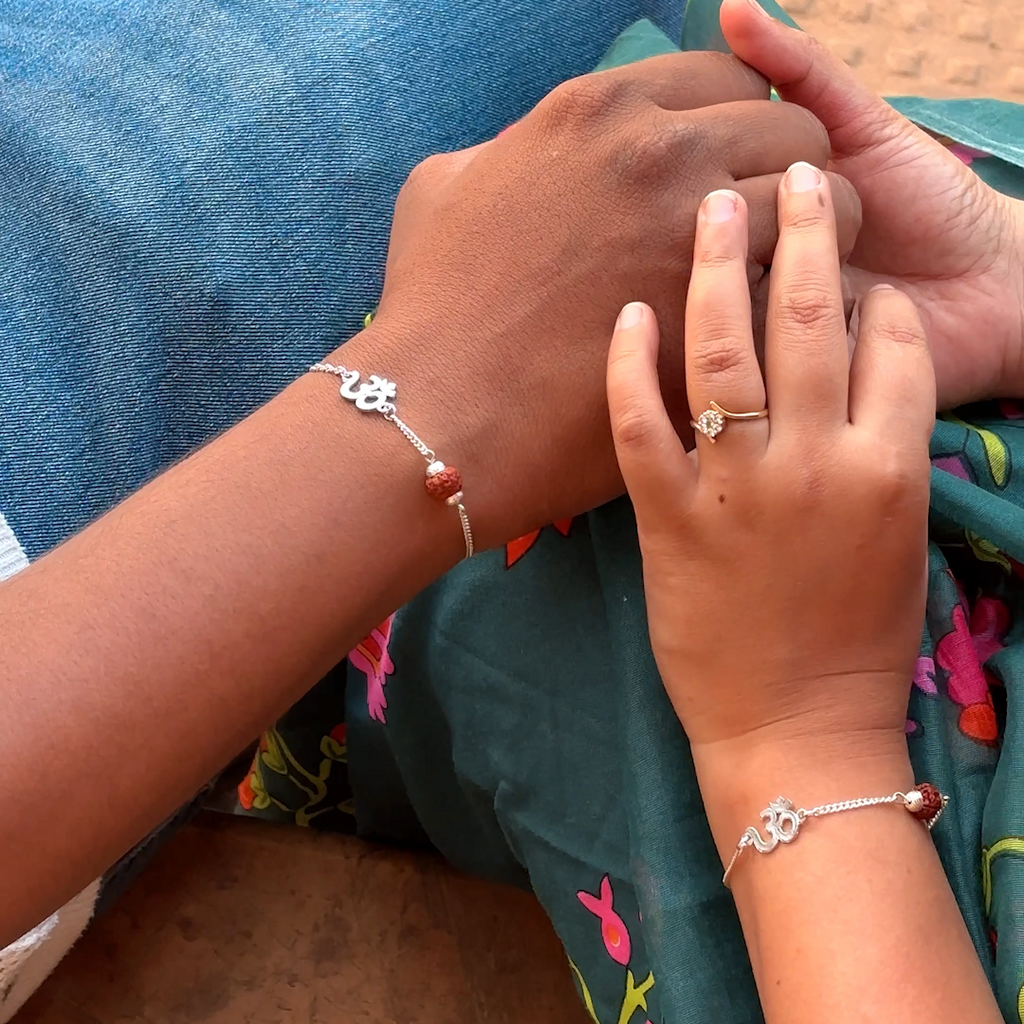 Two hands with bracelets and rings on a textured surface